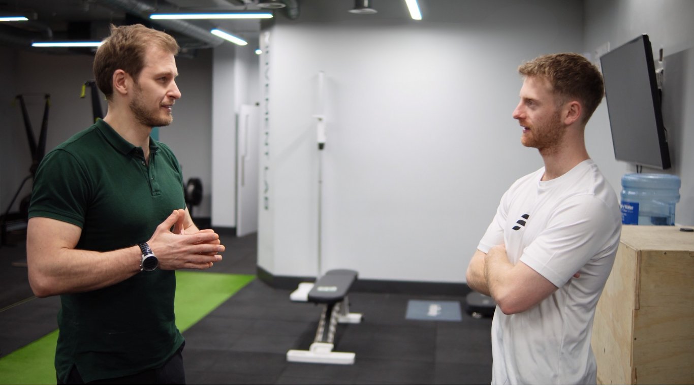 A POL practitioner in conversation with an athlete in the gym